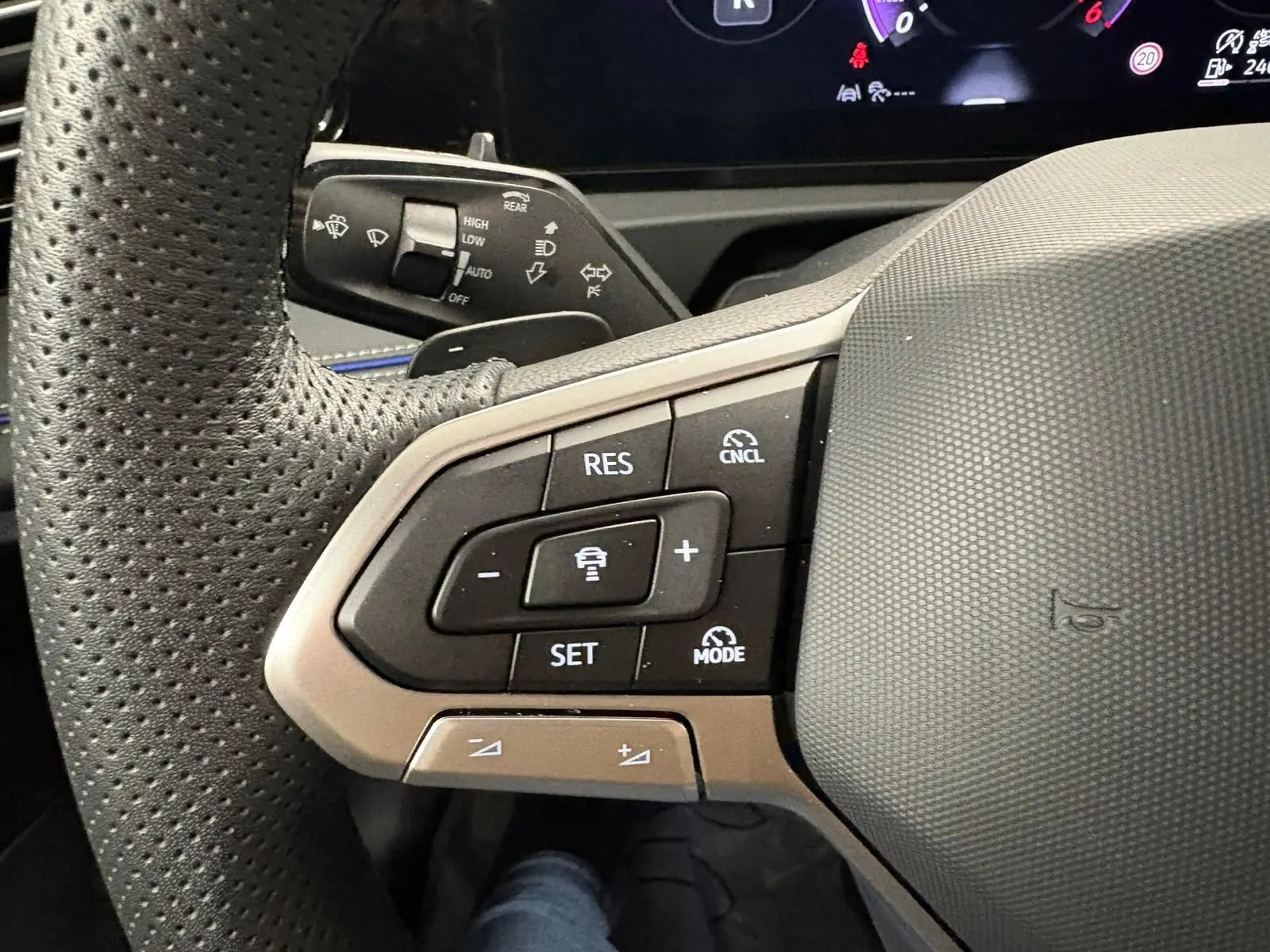 Gros plan sur les commandes au volant à gauche du Volkswagen Tiguan 2024, finition Black R-Line, volant en cuir perforé.