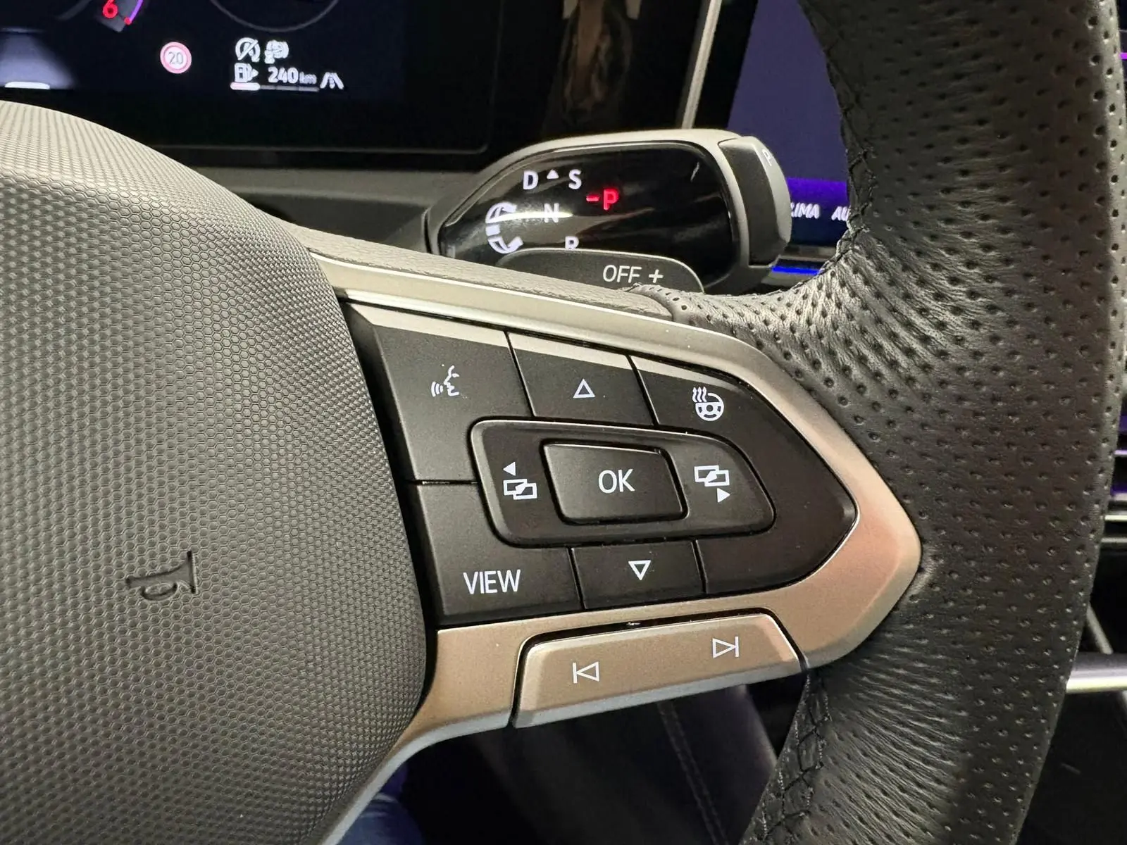 Gros plan sur les commandes multifonctions à droite du volant perforé du Volkswagen Tiguan 2024, intérieur noir.