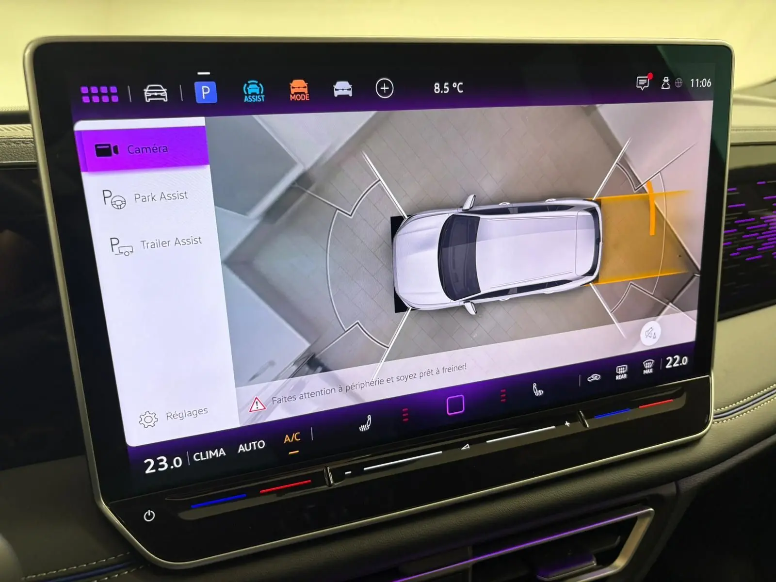 Écran tactile intérieur montrant l'assistance au stationnement avec vue aérienne du Volkswagen Tiguan blanc.