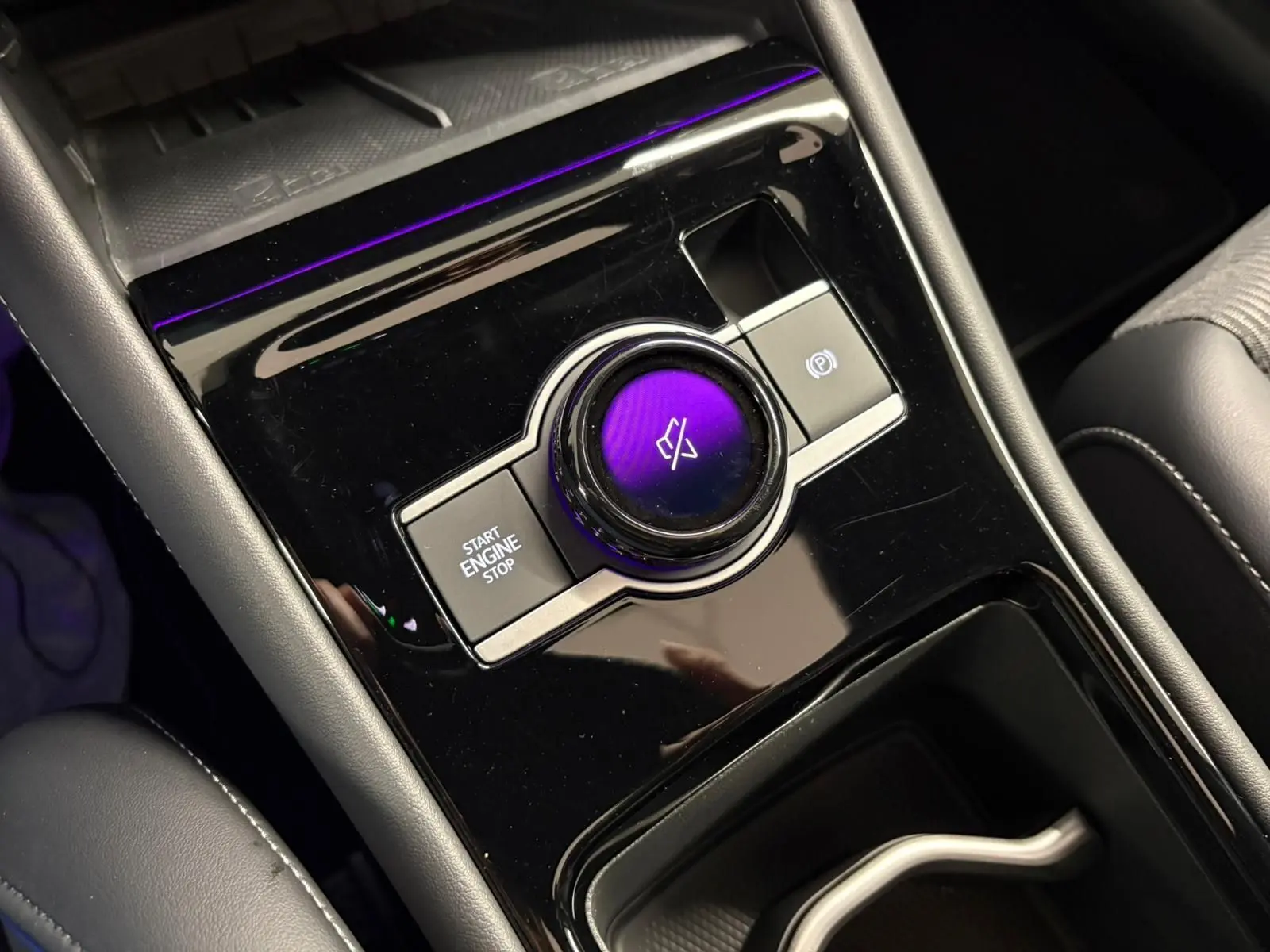 Gros plan sur la console centrale noire brillante du Volkswagen Tiguan 2024 avec bouton start/stop et molette tactile.