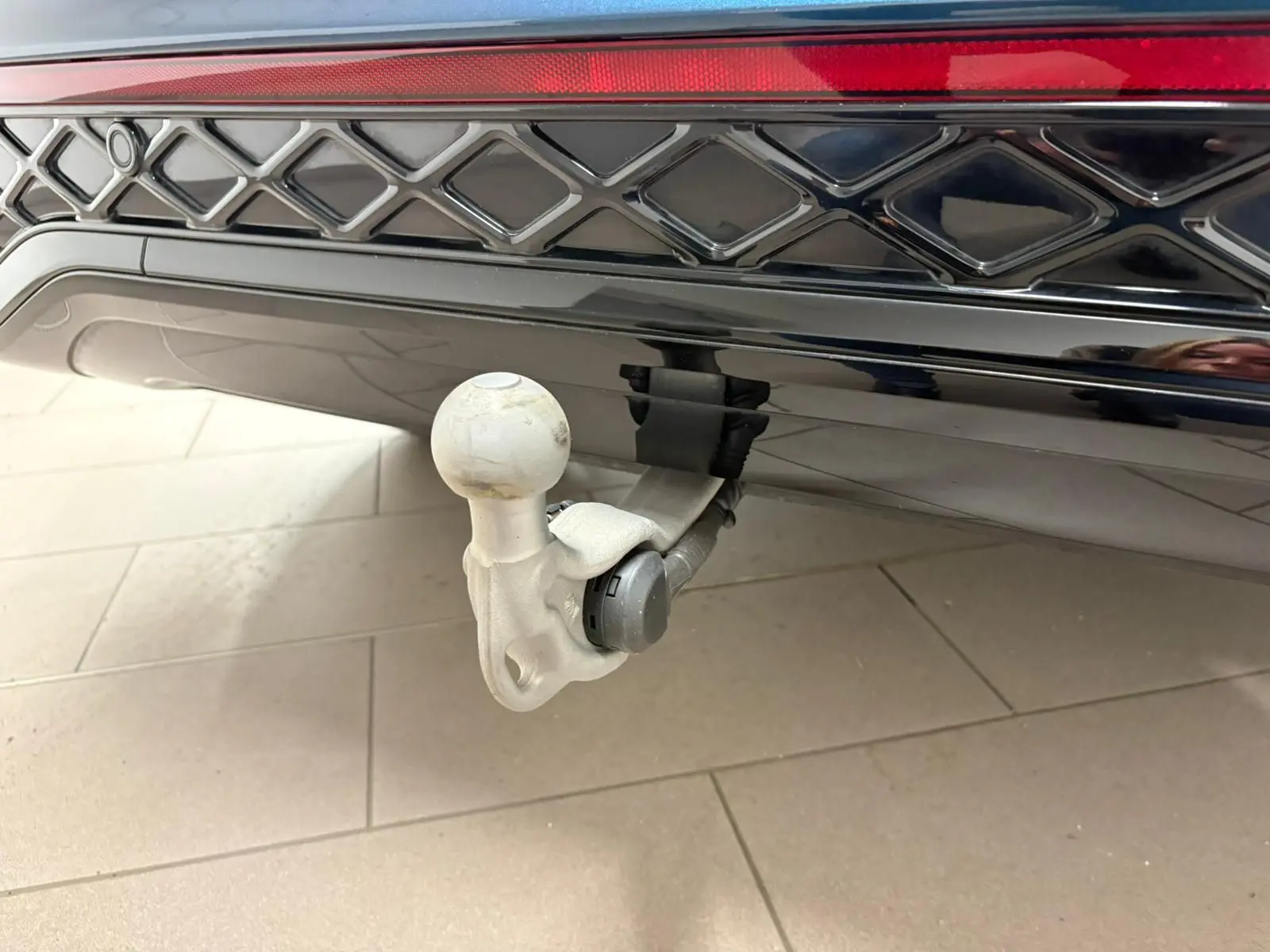 Vue intérieure côté gauche de la porte avant d’un Volkswagen Tiguan Nightshade Blue avec éclairage d’ambiance violet et surpiqûres bleues.