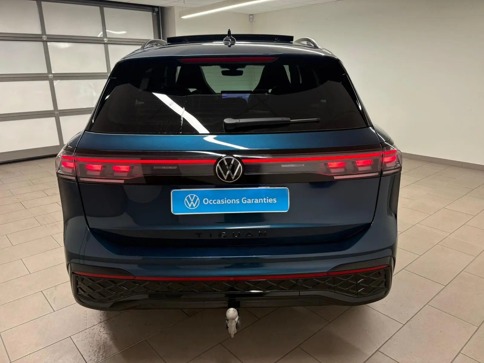 Vue arrière d'un Volkswagen Tiguan 2024 Nightshade Blue avec feux LED et crochet d'attelage escamotable visible.