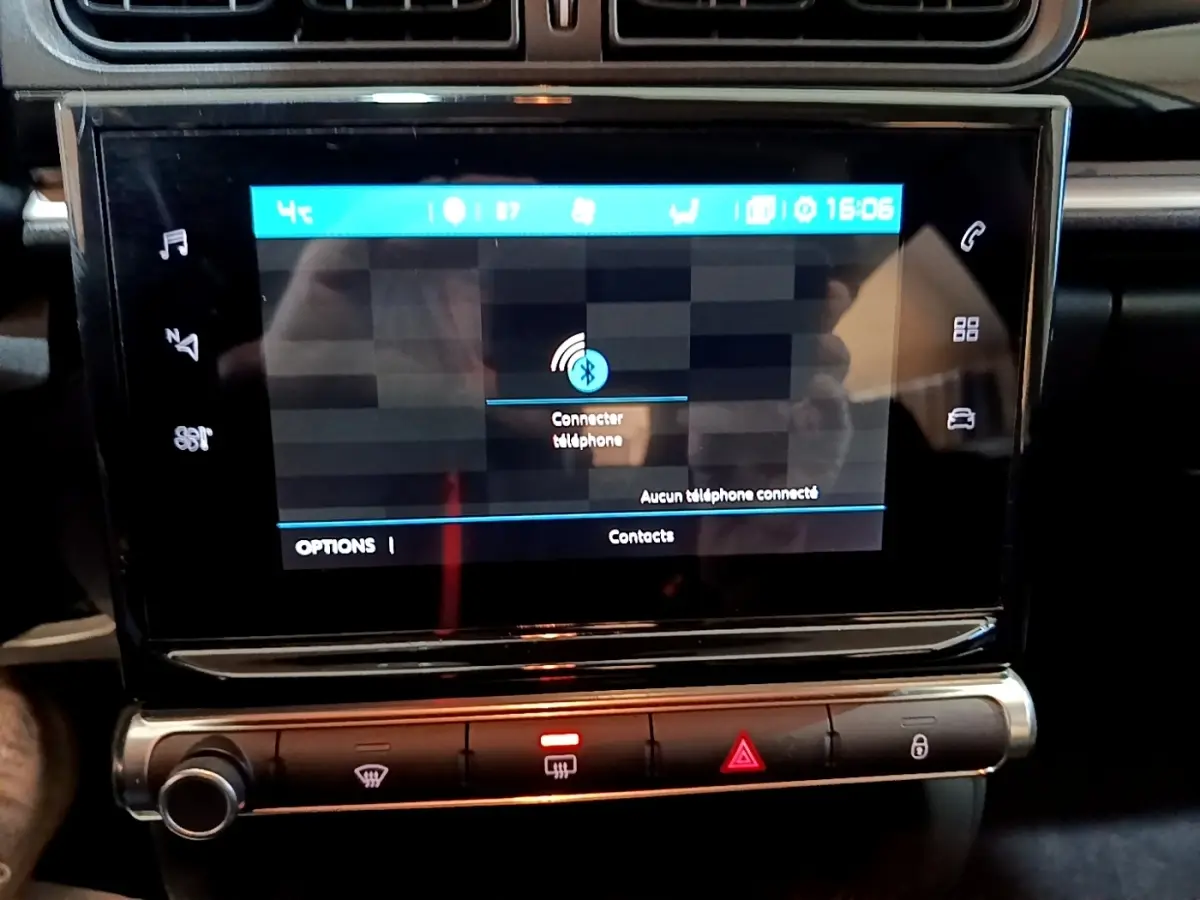 Gros plan sur l'écran tactile central noir de la Citroën C3 blanche, affichant la connexion Bluetooth téléphone.