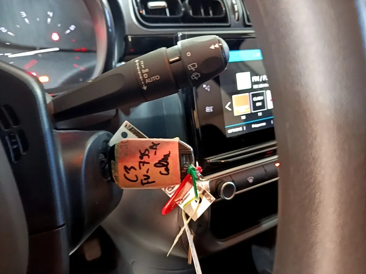 Vue rapprochée du volant et du commodo de la Citroën C3 blanche, avec l'écran tactile du tableau de bord en arrière-plan.