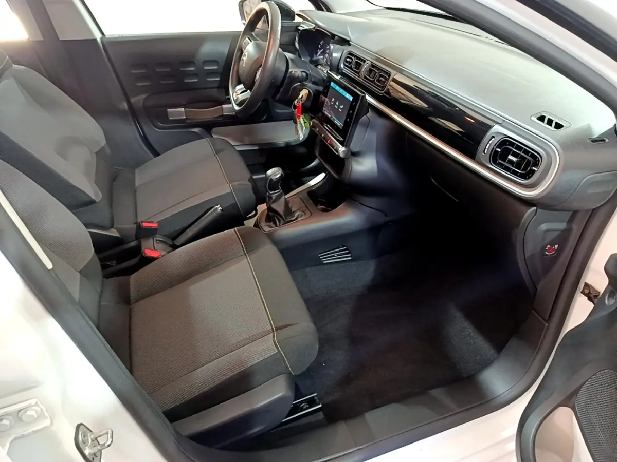 Intérieur avant droit de la Citroën C3 blanche 2020, montrant sièges tissu noirs et tableau de bord avec écran tactile.