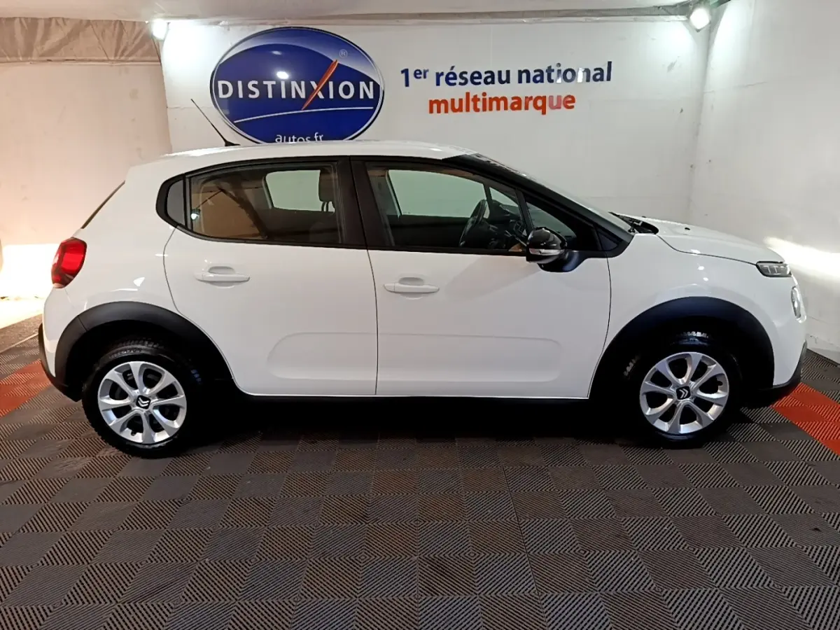 Profil côté gauche d'une Citroën C3 blanche 2020, avec protections noires sur les passages de roues et jantes argentées.