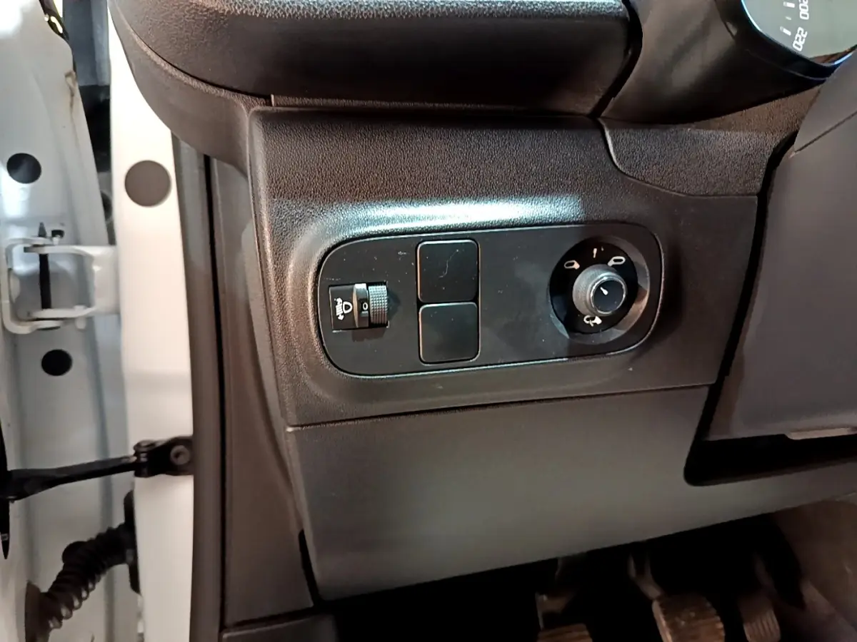 Vue rapprochée côté gauche du tableau de bord noir de la Citroën C3 blanche, avec commandes des phares et rétroviseurs.