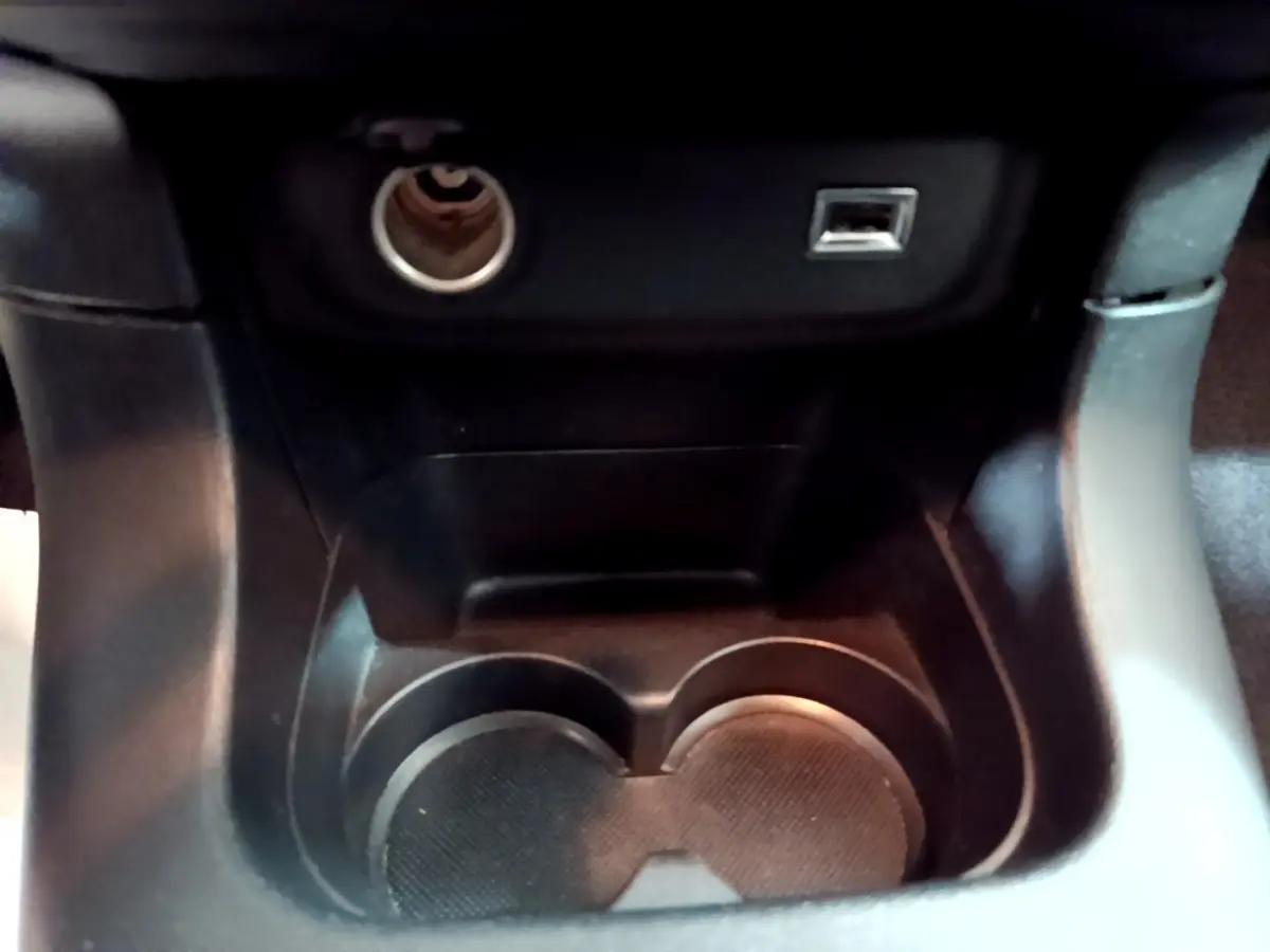 Gros plan sur la console centrale noire de la Citroën C3 avec prise allume-cigare et port USB visibles.