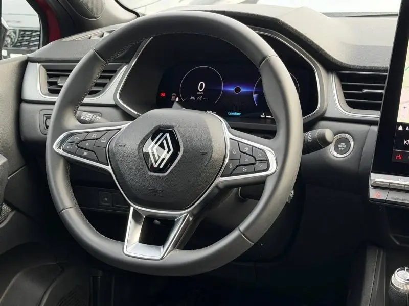 Vue intérieure centrée sur le volant noir du Renault Captur 2025 avec tableau de bord numérique et bouton start/stop visible.