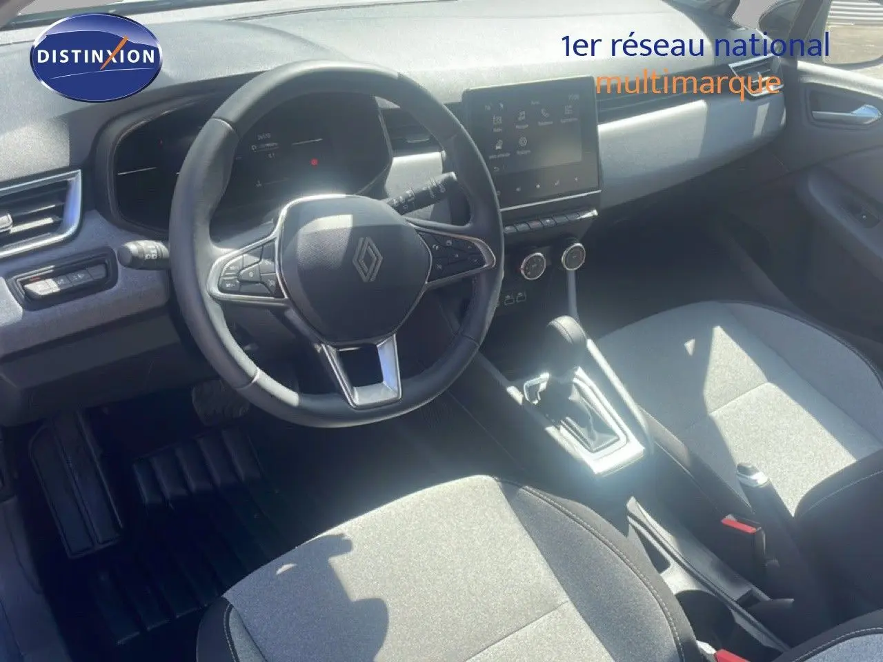 Vue intérieure de face de la Renault Clio blanche 2025, montrant le volant multifonction et l’écran tactile central.