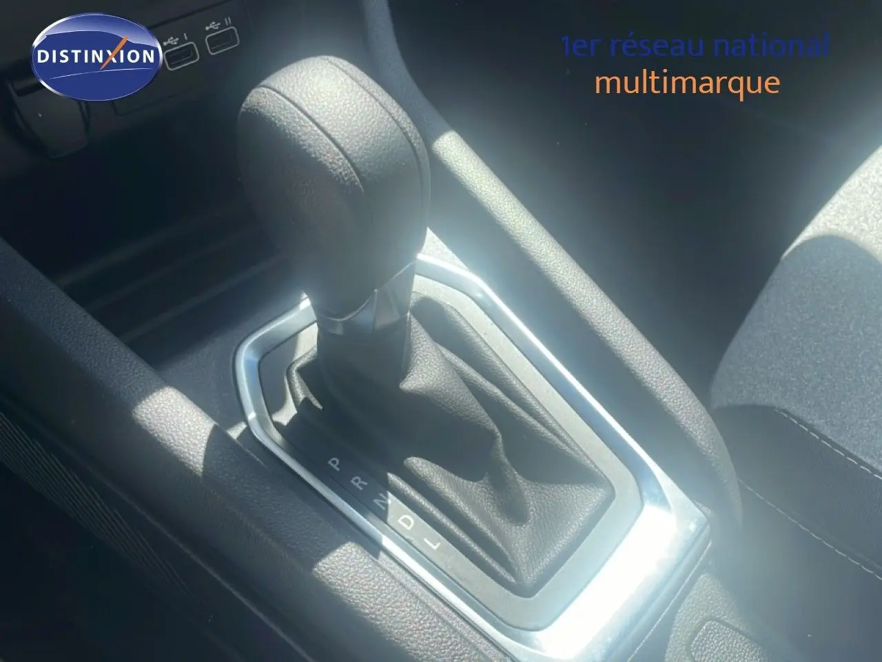 Gros plan sur le levier de vitesse automatique noir de la Renault Clio blanche, version 2025, intérieur tissu noir.