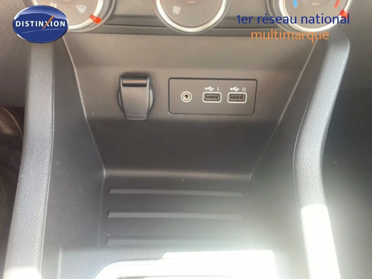 Gros plan sur la console centrale noire de la Renault Clio 2025 montrant deux ports USB et une prise jack audio.