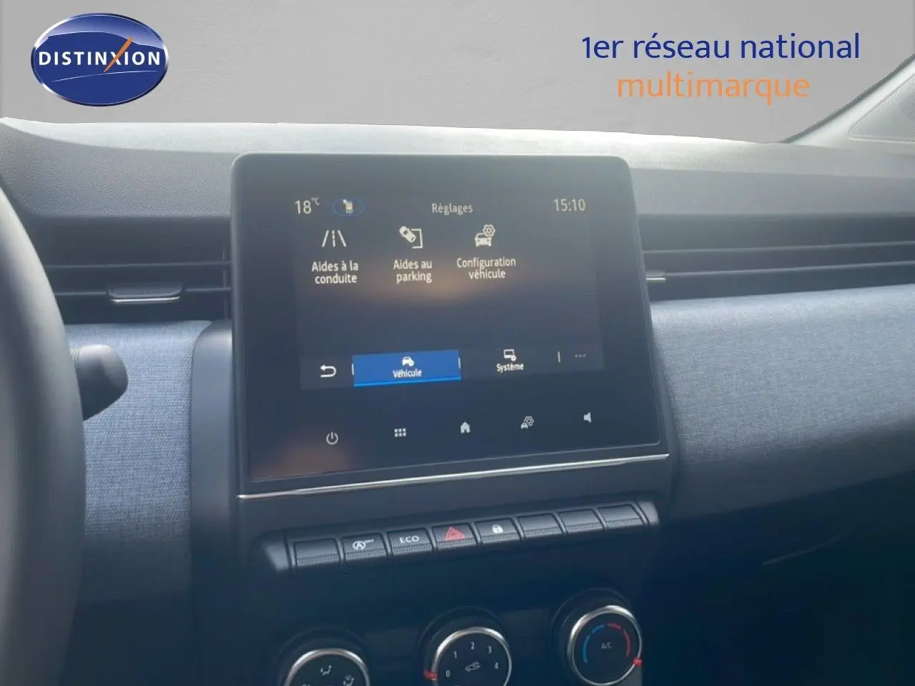 Vue intérieure du tableau de bord de la Renault Clio blanche 2025, avec écran tactile et commandes de climatisation visibles.