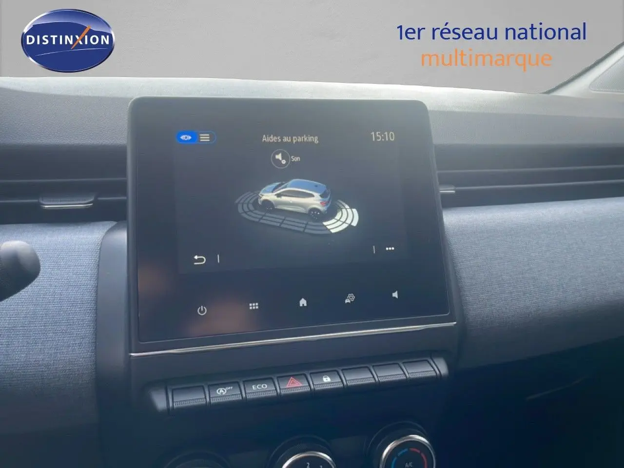 Vue rapprochée de l’écran tactile central affichant l’aide au parking dans l’habitacle d’une Renault Clio blanche.