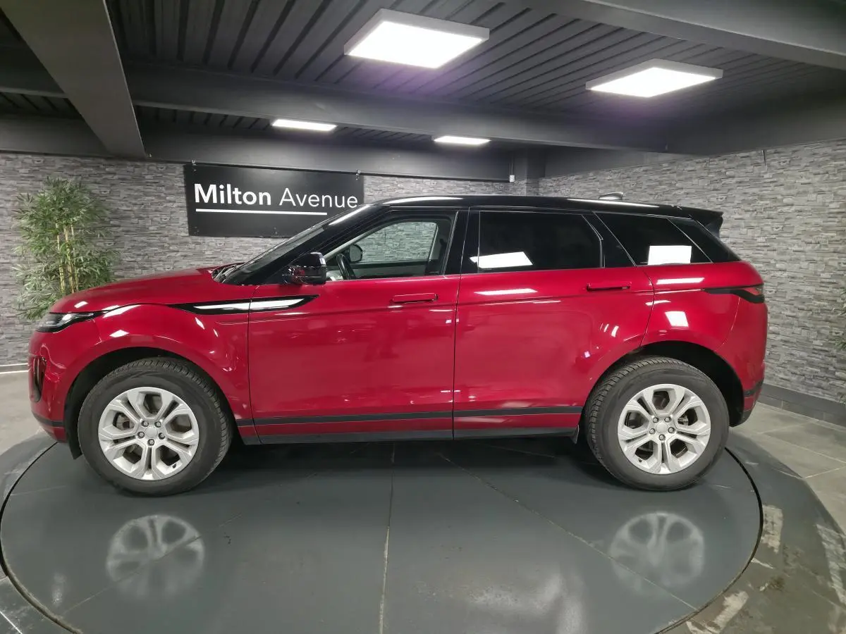 Vue de profil côté gauche d'un Range Rover Evoque 2019 rouge avec toit noir dans un showroom intérieur.
