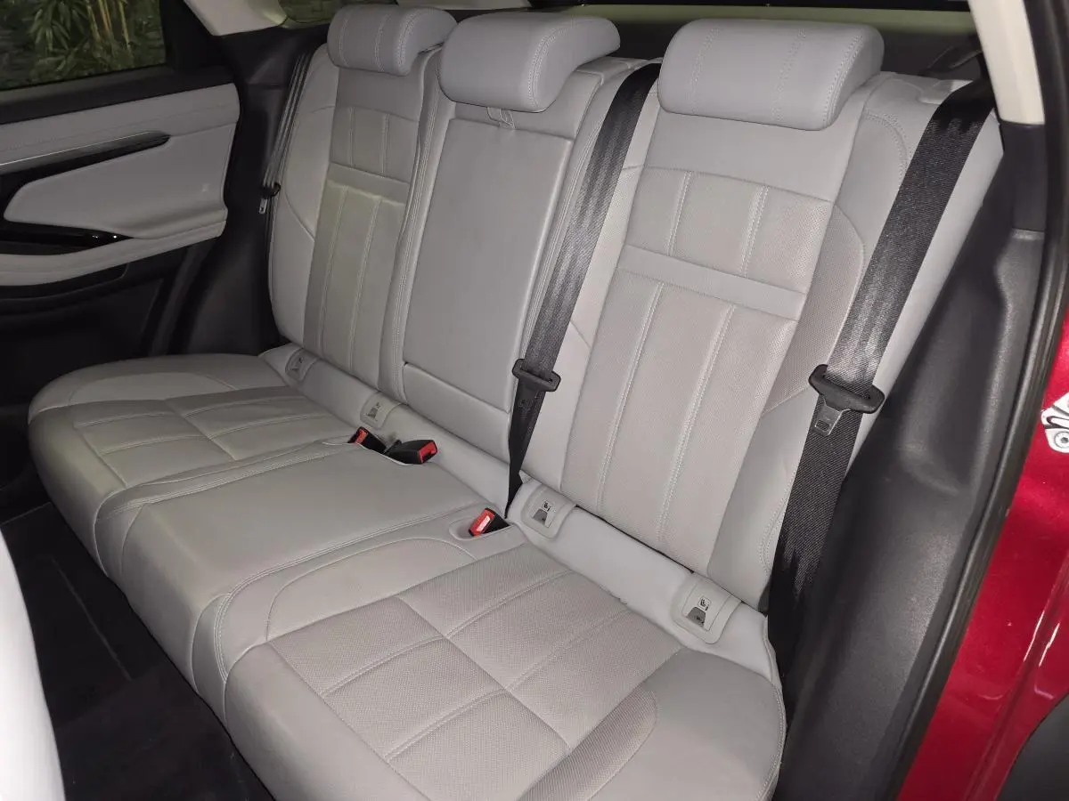 Vue intérieure des sièges arrière en cuir gris clair du Range Rover Evoque rouge, avec ceintures de sécurité visibles.