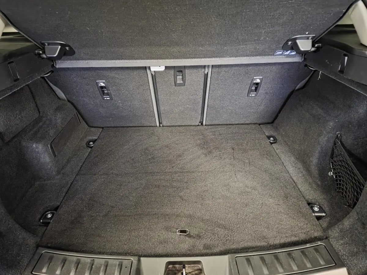 Coffre ouvert vu de l'arrière du Range Rover Evoque rouge, espace de chargement vide et revêtement noir.