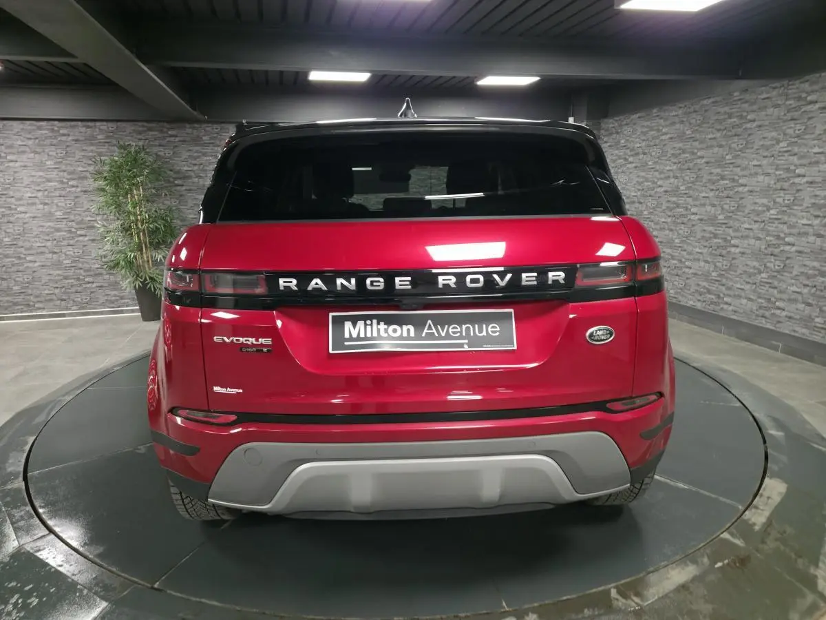 Vue arrière d'un Range Rover Evoque rouge avec toit noir et logo distinctif sur un plateau tournant intérieur.