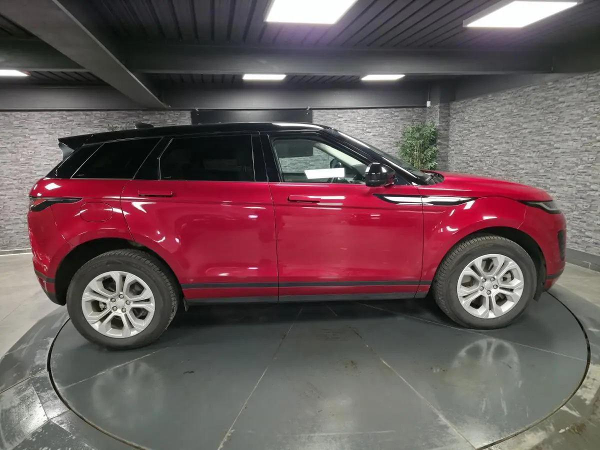 Vue de profil côté gauche d'un Range Rover Evoque rouge avec toit noir contrasté dans un showroom intérieur.