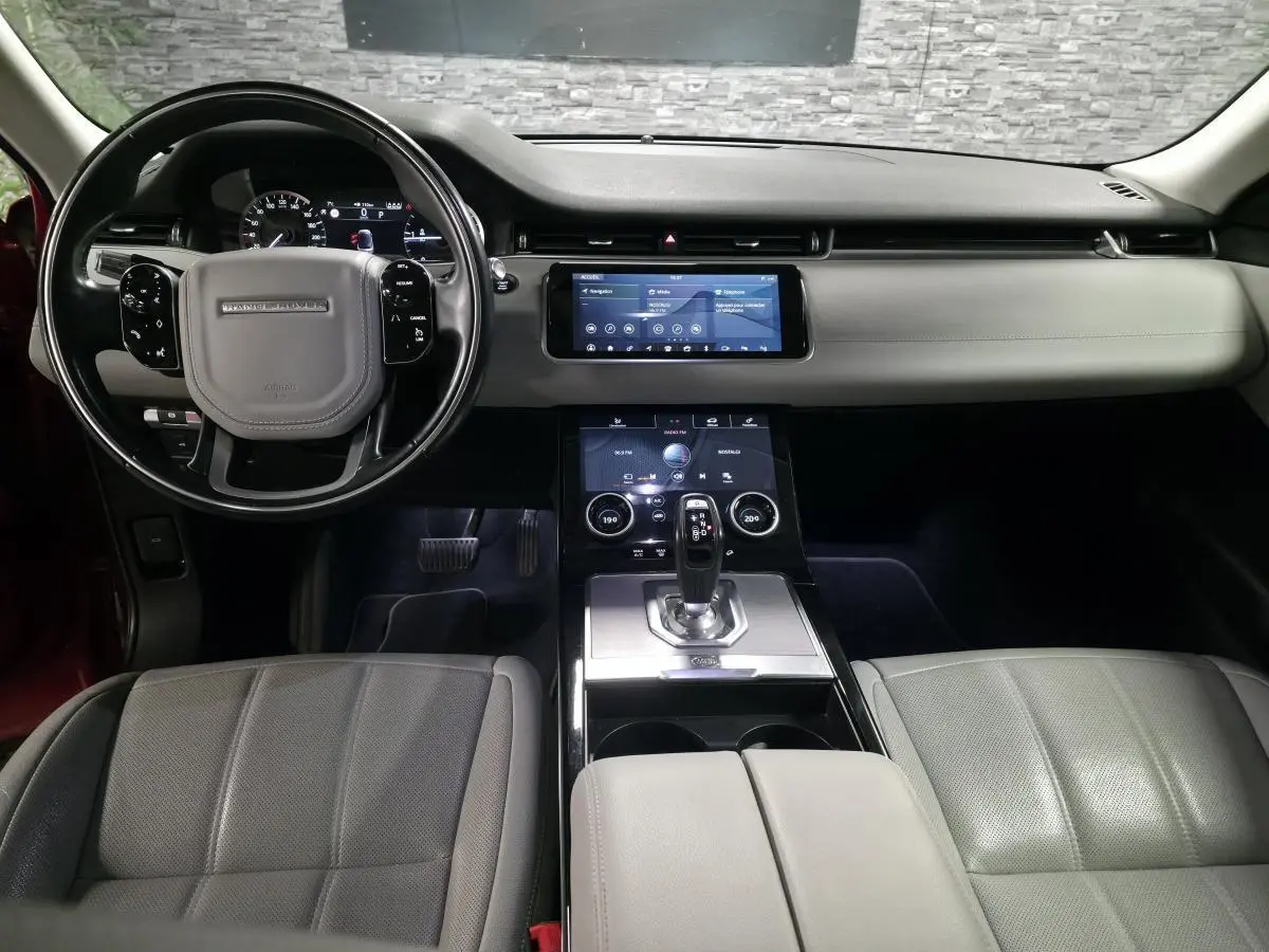 Vue intérieure avant du Range Rover Evoque 2019 avec tableau de bord noir et sièges cuir gris clair.