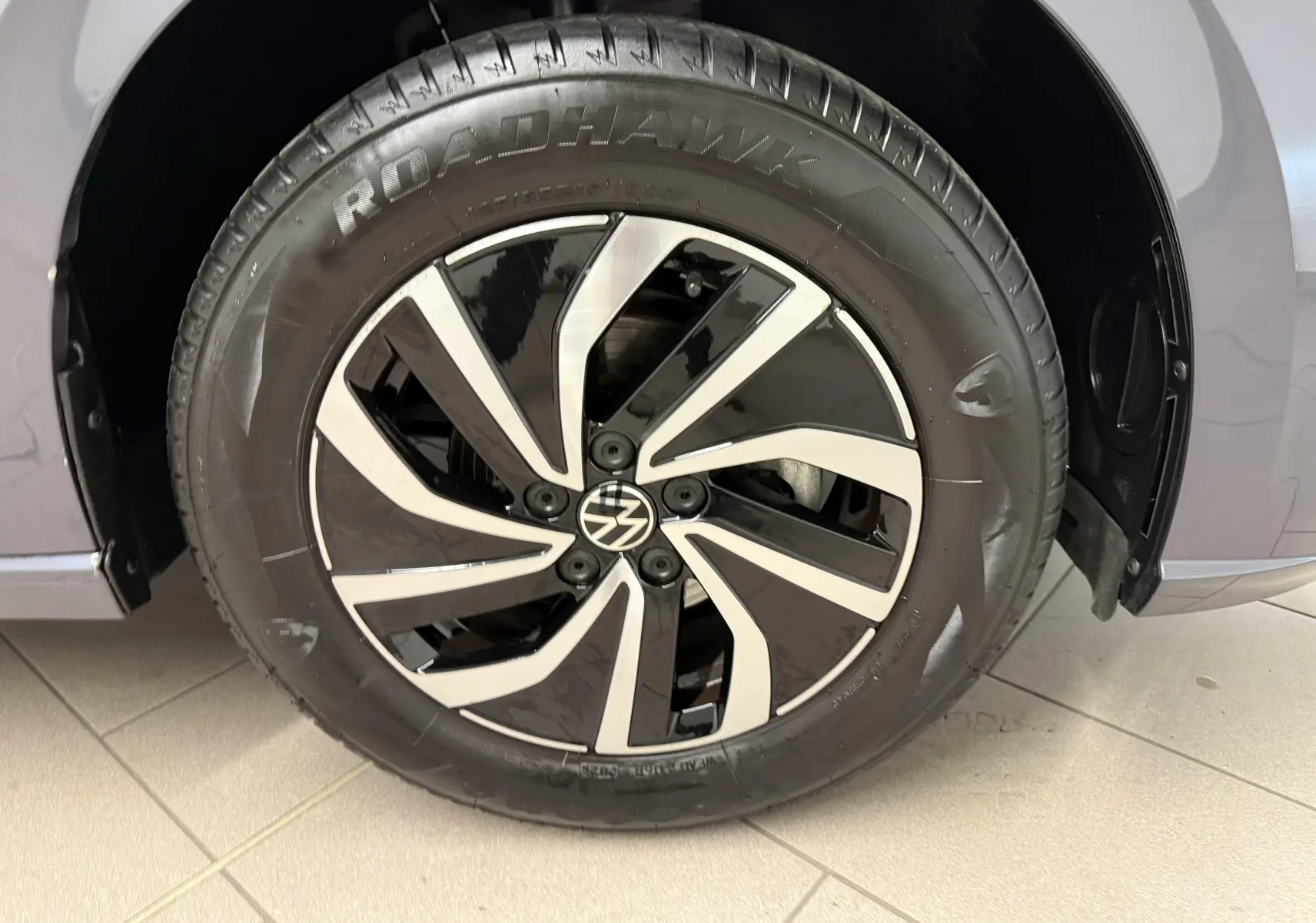 Gros plan sur la jante alliage 15'' bicolore et pneu Roadhawk d'une Volkswagen Polo gris cendre côté droit.