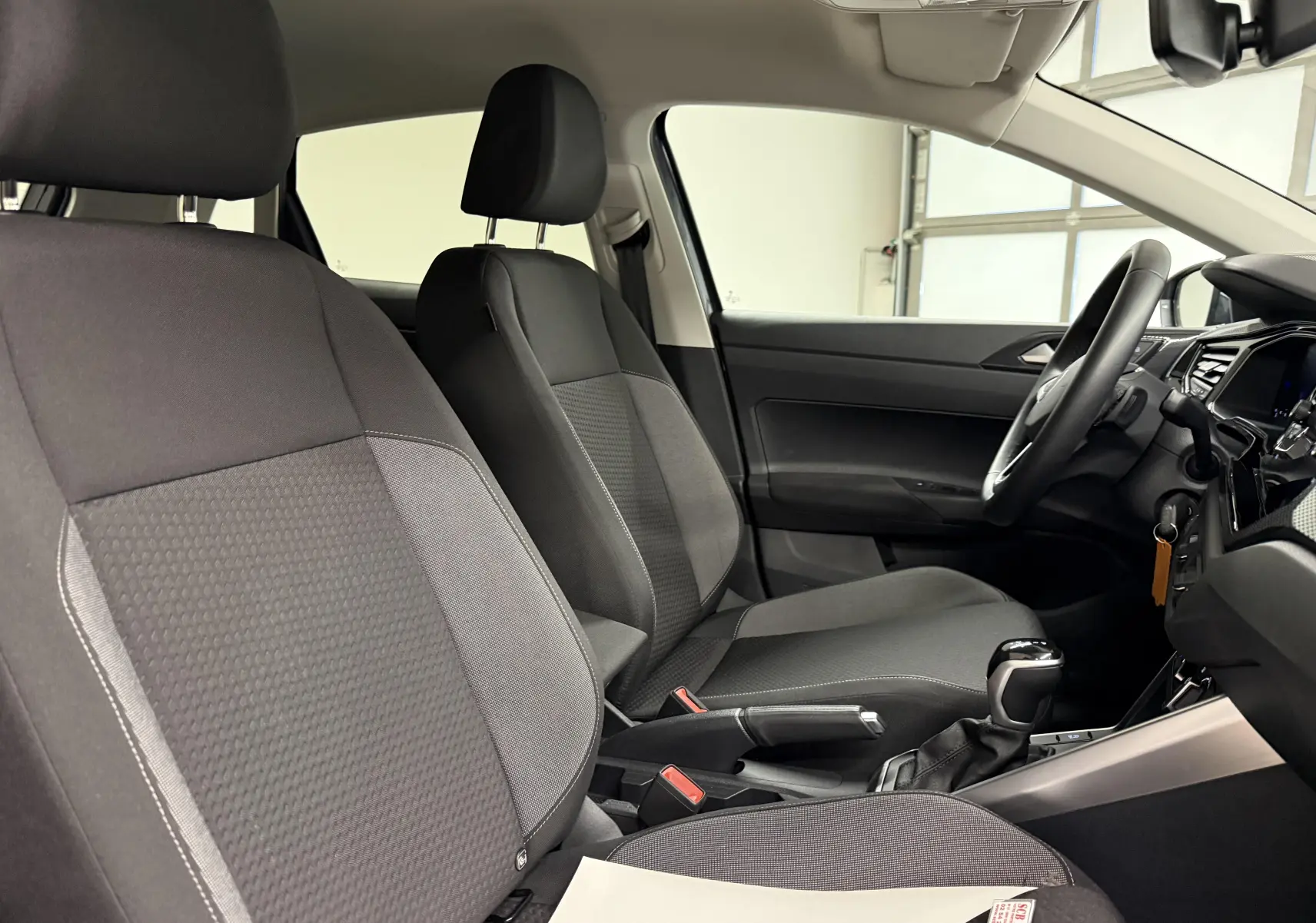 Vue intérieure côté droit montrant les sièges avant gris foncé et la console centrale avec levier de vitesses automatique d'une Volkswagen Polo 2025.