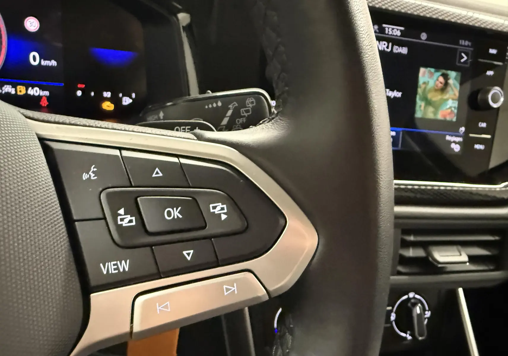 Vue rapprochée du volant cuir noir avec commandes multifonctions et écran tactile du tableau de bord d'une Volkswagen Polo gris cendre 2025.