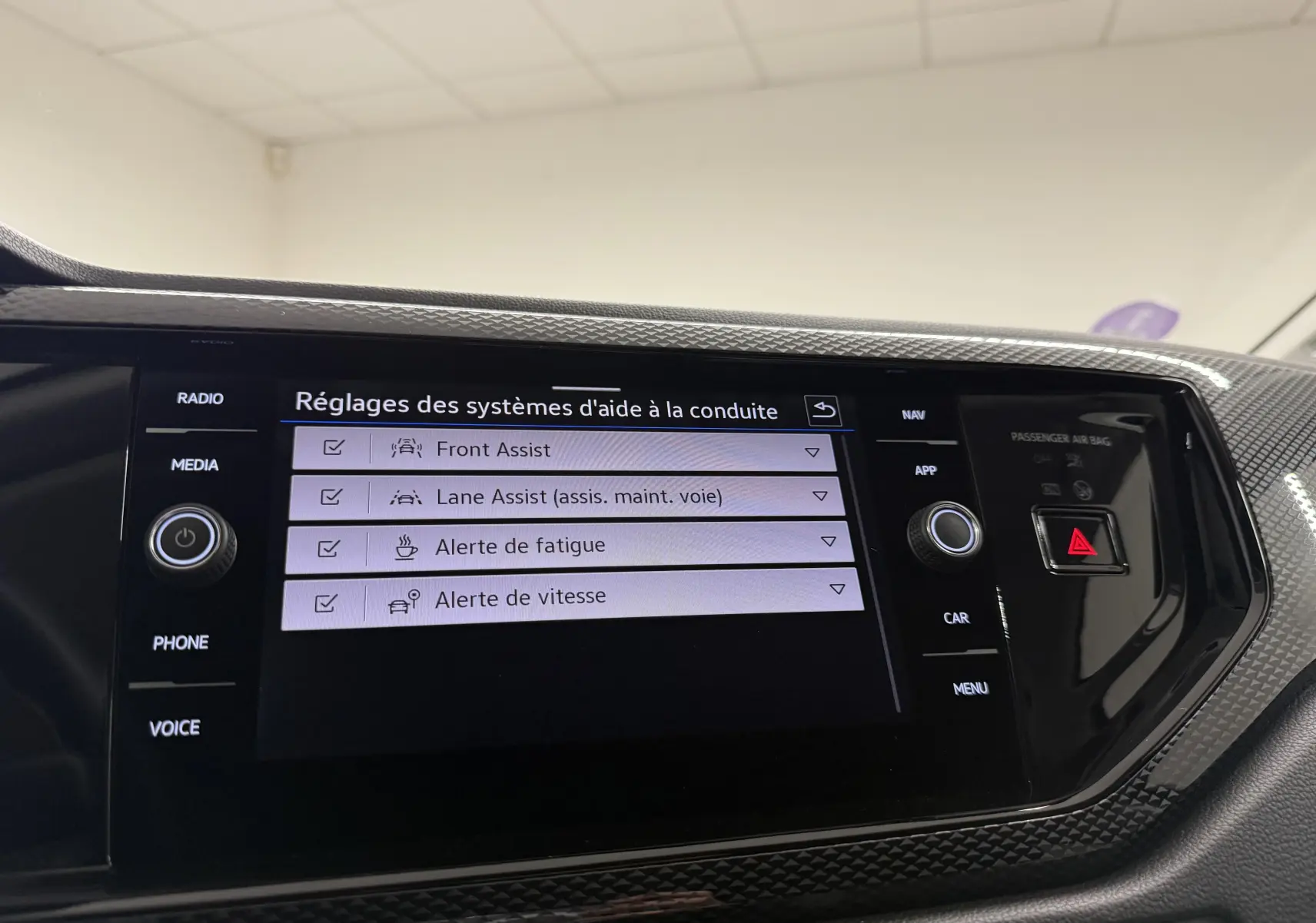 Écran tactile central de la Volkswagen Polo gris cendre affichant les réglages des aides à la conduite.