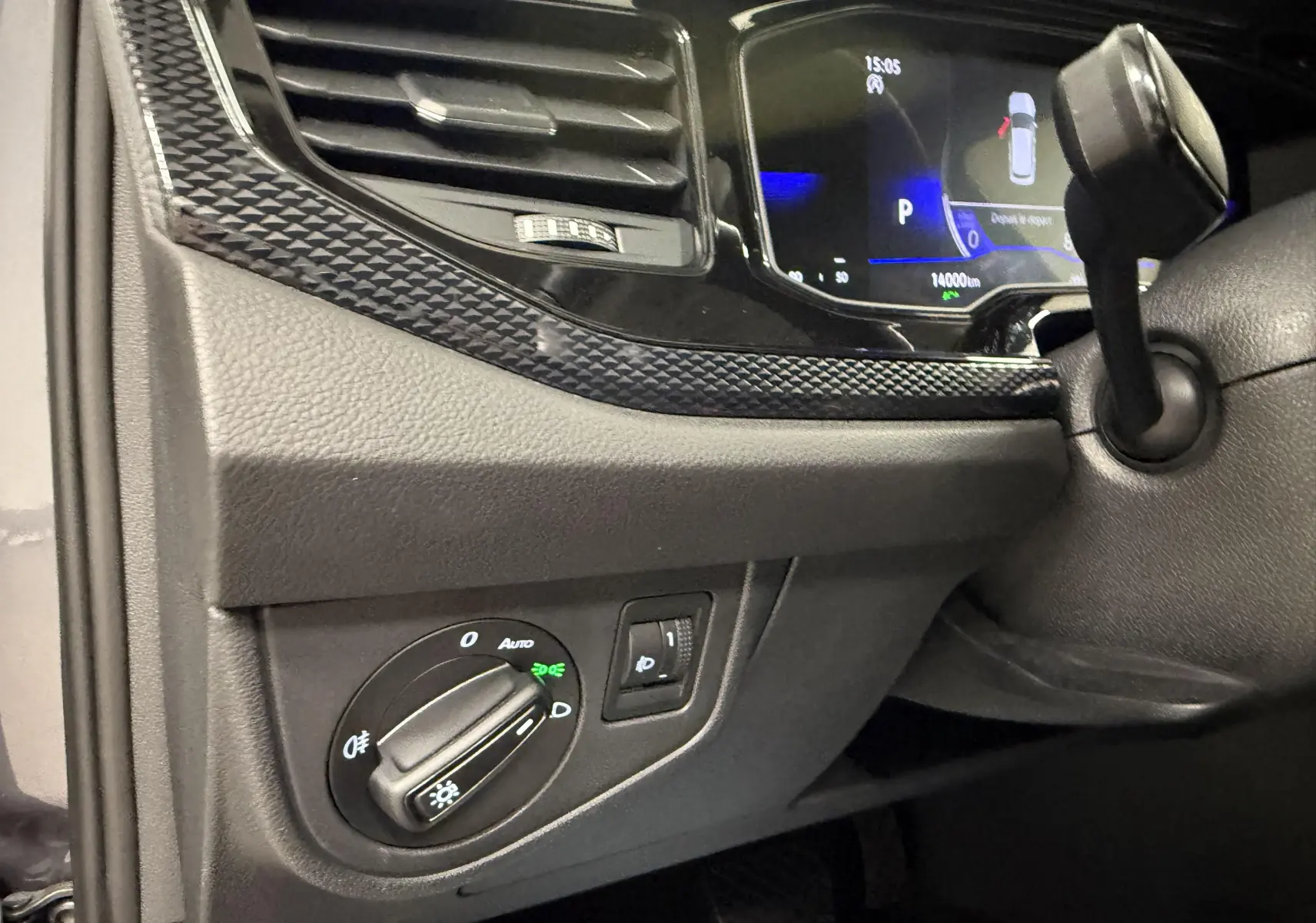 Détail du tableau de bord côté gauche d'une Volkswagen Polo gris cendre, avec commandes d'éclairage et combiné digital.