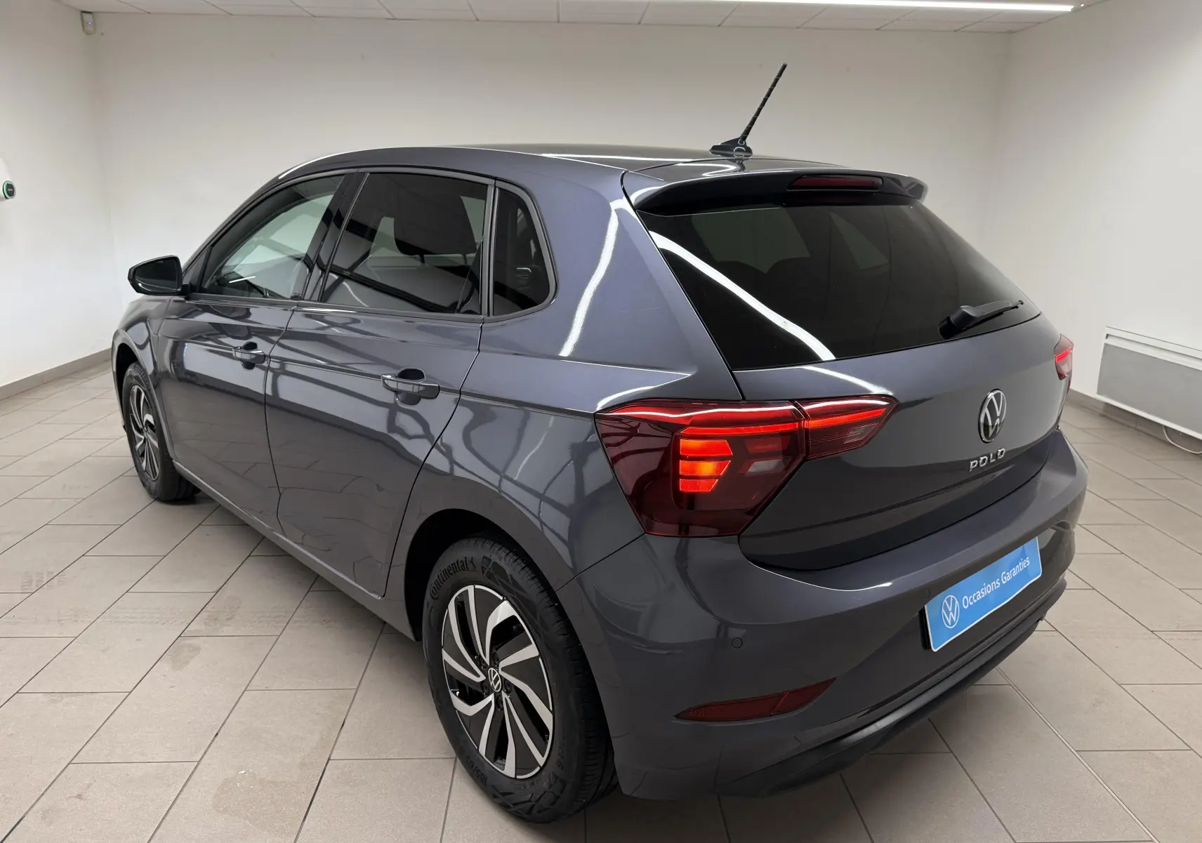 Vue 3/4 arrière droite d'une Volkswagen Polo gris cendre avec vitres surteintées et jantes alliage distinctives.