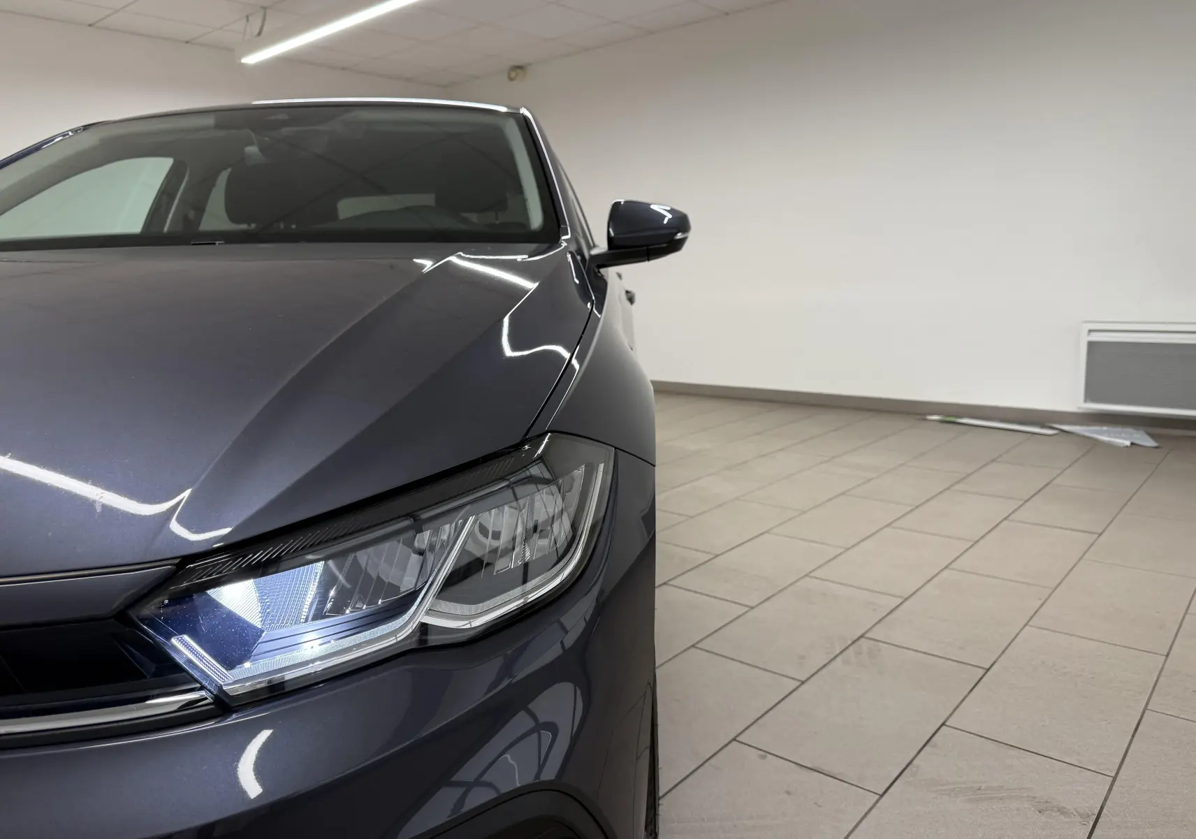 Vue rapprochée 3/4 avant gauche du Volkswagen Polo gris cendre mettant en valeur le phare LED et la calandre.