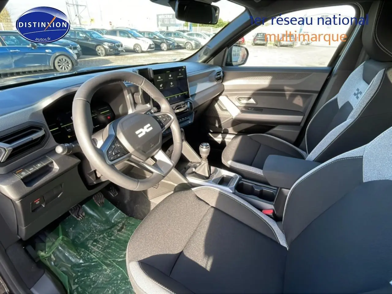 Intérieur avant du Dacia Duster 2026, vue côté conducteur, volant multifonction et sièges bi-ton gris et noir.