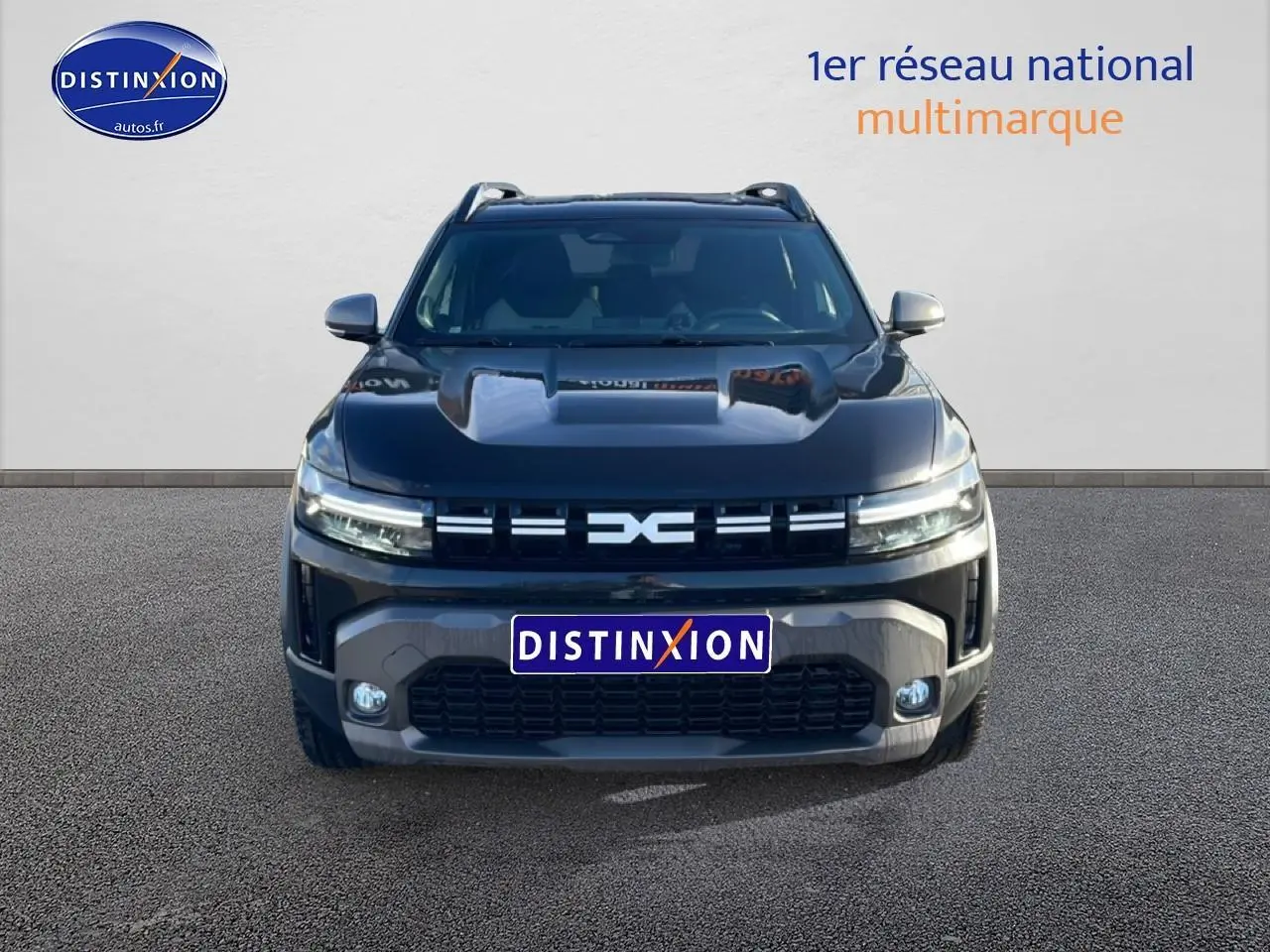 Vue avant du Dacia Duster noir 2026 avec calandre distinctive et phares LED allumés sur fond neutre.
