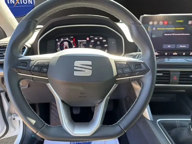 Vue rapprochée du volant cuir et alu du SEAT Leon 2025 avec tableau de bord numérique et écran tactile central.
