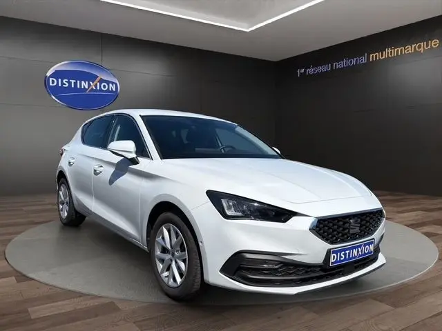 SEAT Leon 2.0 TDI blanc vue 3/4 avant en intérieur, avec calandre noire et jantes argentées.