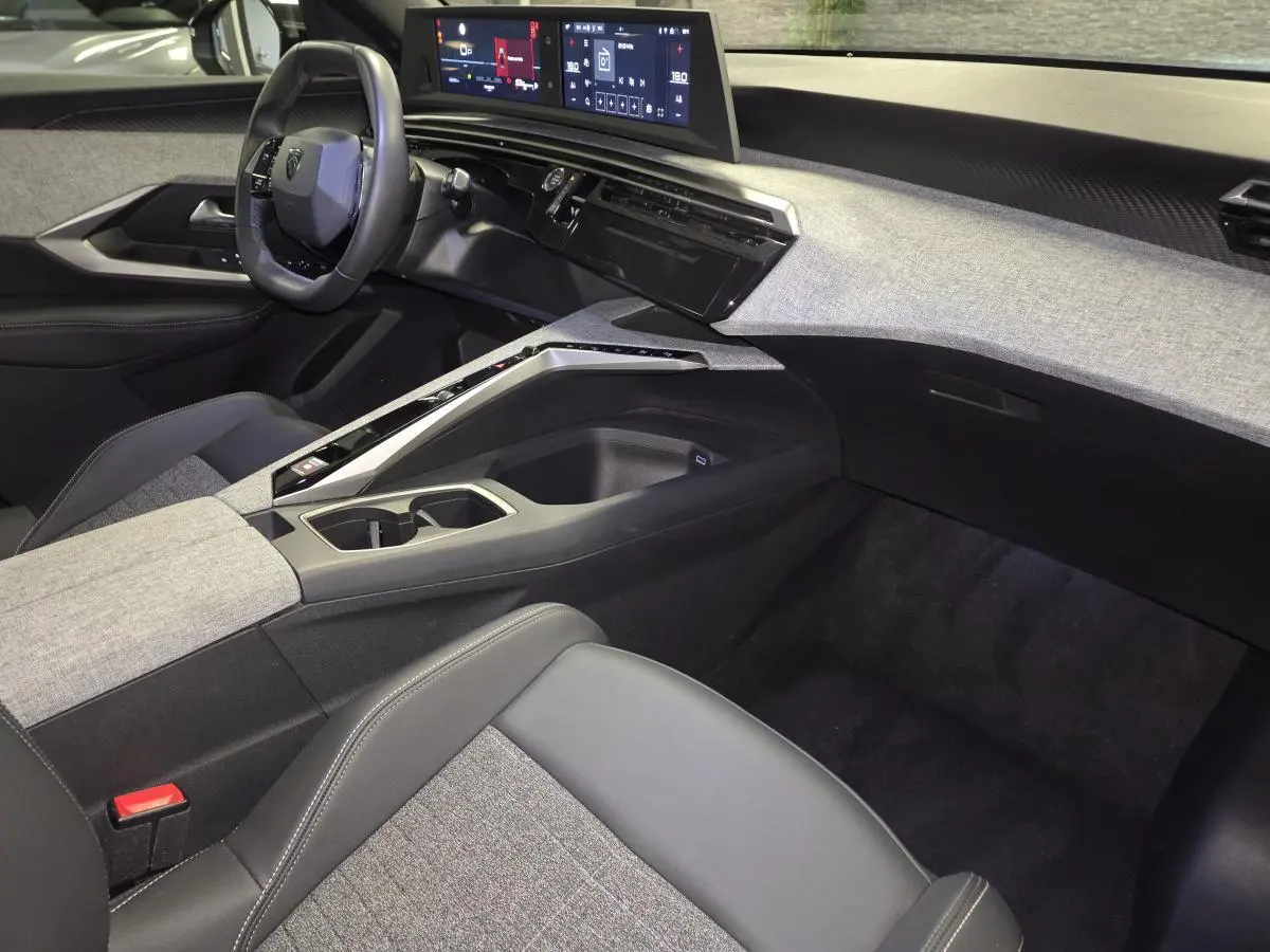 Intérieur avant droit du Peugeot 3008 2025 hybride avec tableau de bord tissu gris et double écran HD flottant.