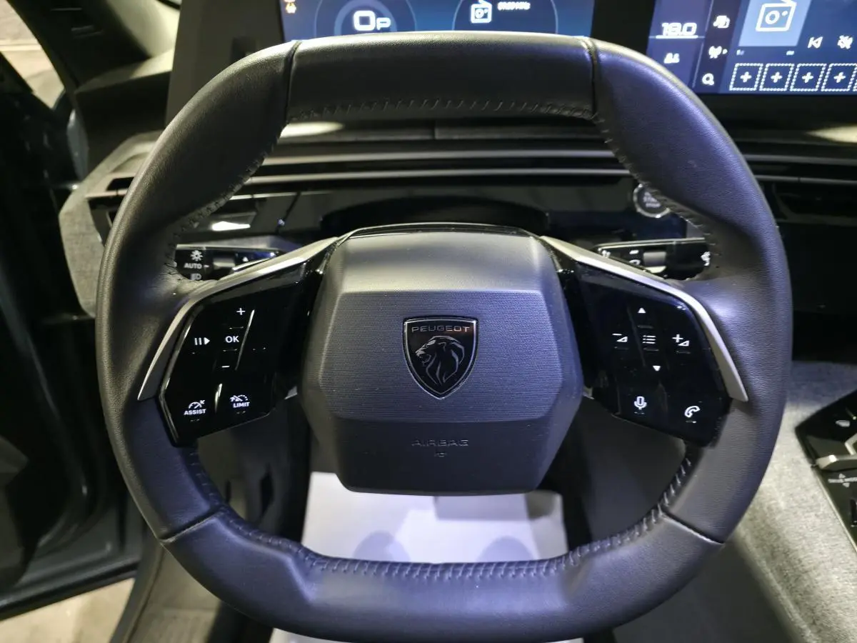 Vue rapprochée du volant noir cuir du Peugeot 3008 2025 avec commandes intégrées et logo lion central.