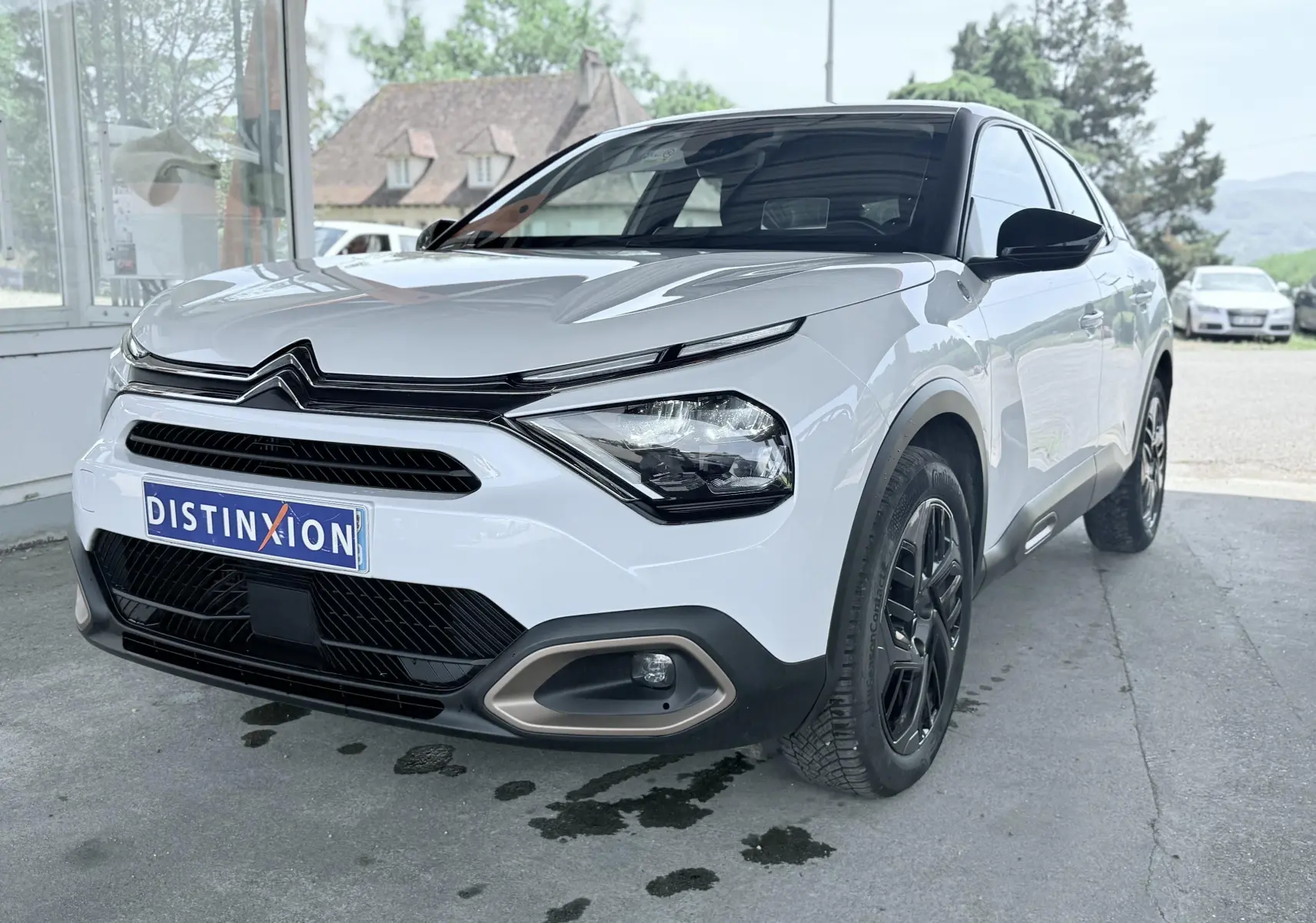 Citroën C4 blanc vue 3/4 avant droit, avec calandre noire et jantes noires contrastantes.