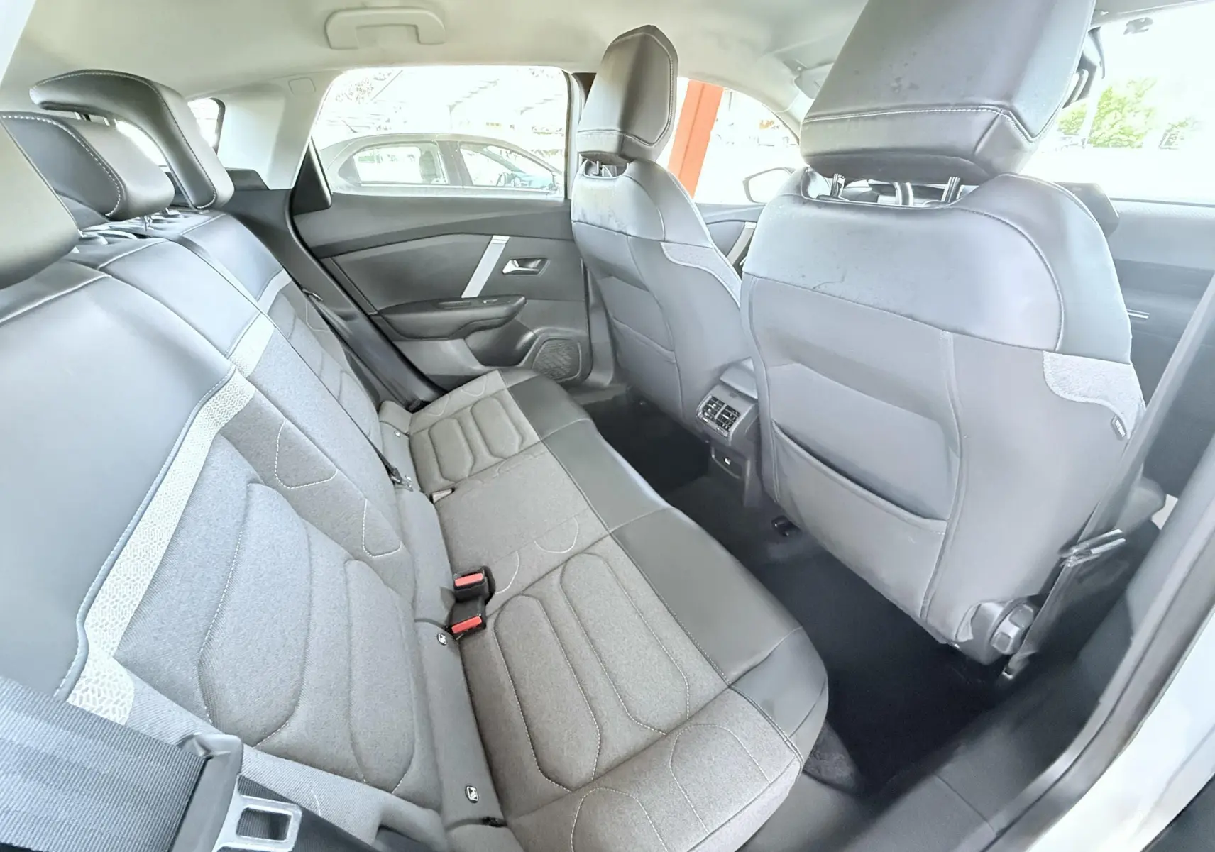 Vue intérieure arrière côté droit de la Citroën C4 2023, sièges tissu gris et cuir noir avec appuie-têtes intégrés.