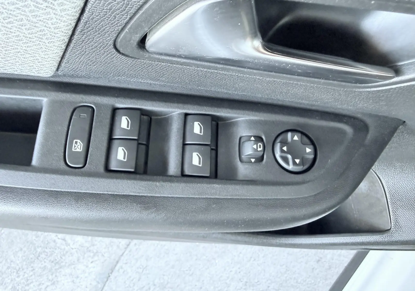 Gros plan sur les commandes de lève-vitres et rétroviseurs sur la porte côté gauche d'une Citroën C4 blanche.