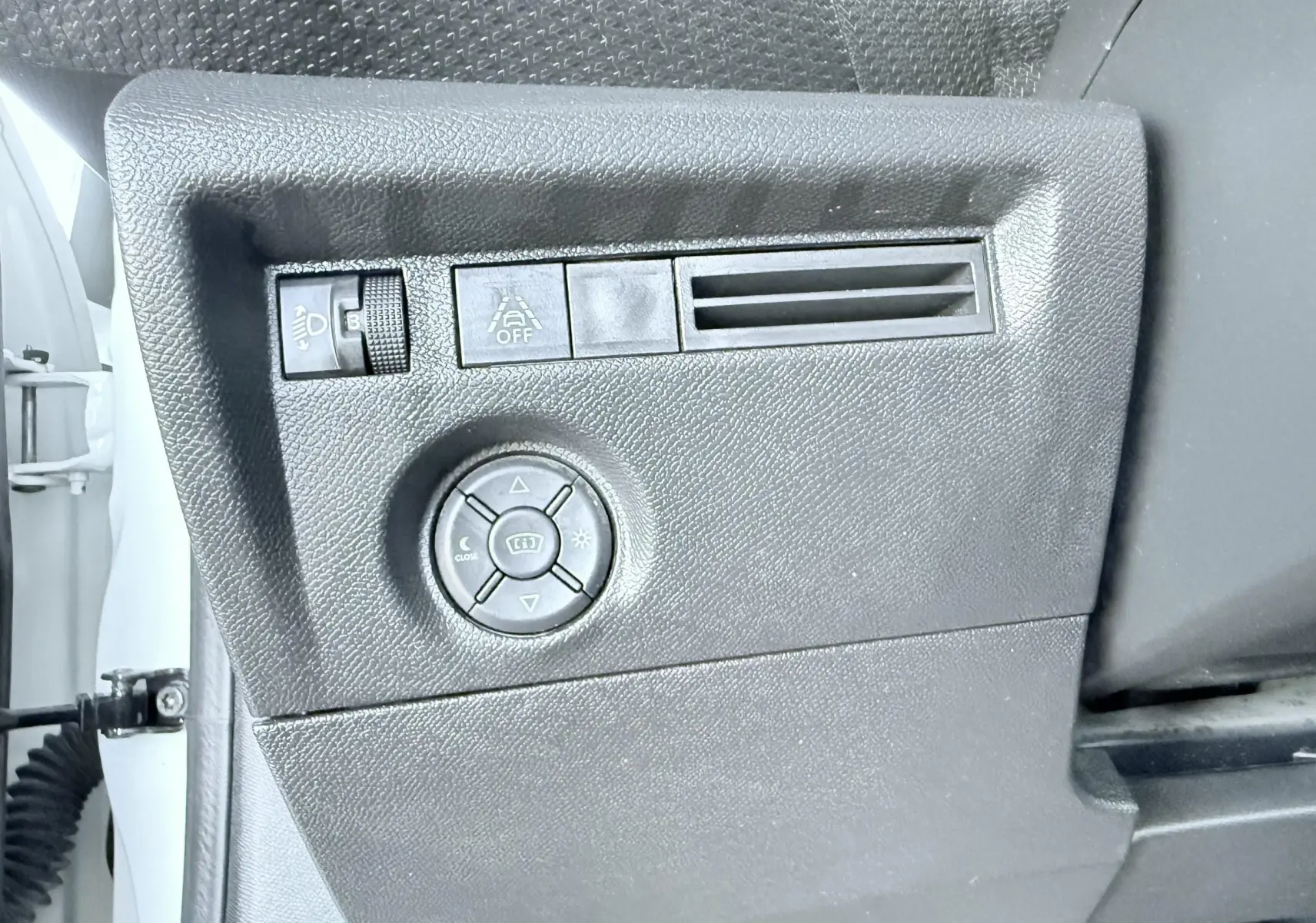Vue rapprochée du panneau de commandes latéral noir à gauche dans une Citroën C4 blanche de 2023.
