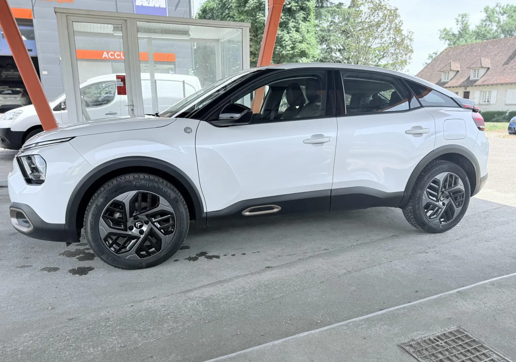 Profil droit d'une Citroën C4 blanche 2023 avec toit noir et jantes noires au design moderne.