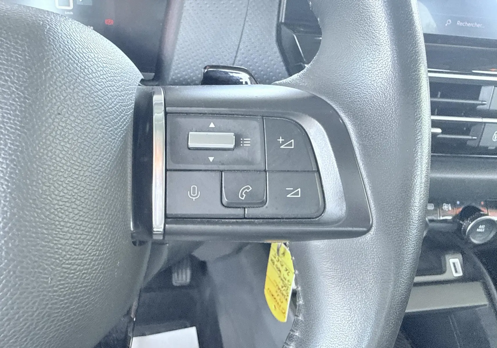 Gros plan sur les commandes vocales et téléphone sur le côté gauche du volant noir d'une Citroën C4 2023.
