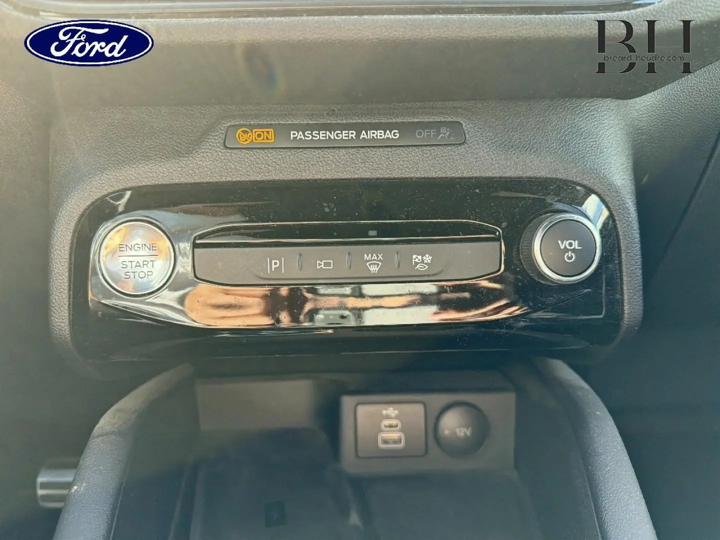 Gros plan sur la console centrale du Ford Kuga 2024, boutons de démarrage, volume et ports USB visibles.