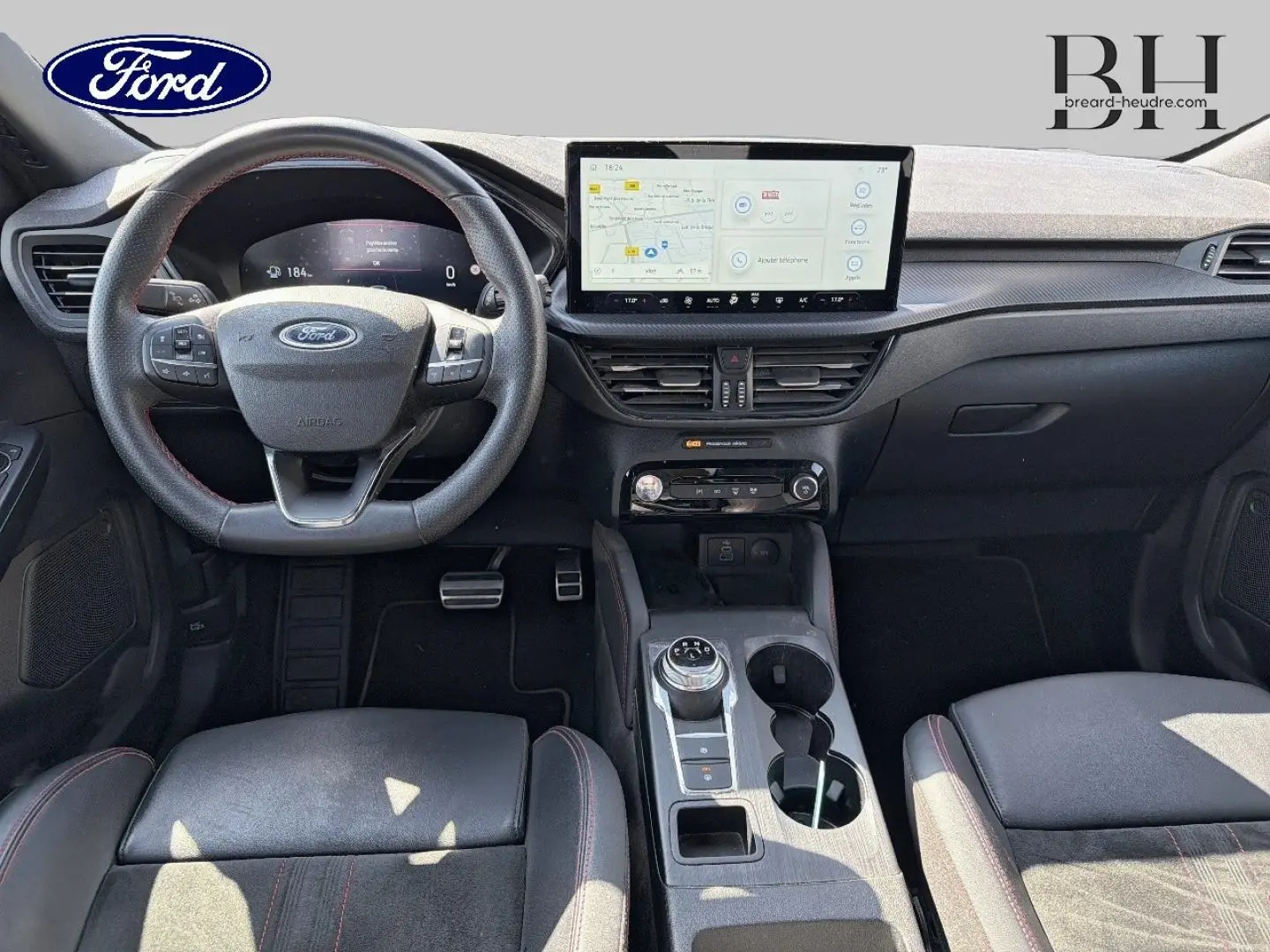 Vue intérieure frontale du Ford Kuga 2024, tableau de bord noir avec écran tactile central et volant multifonction.