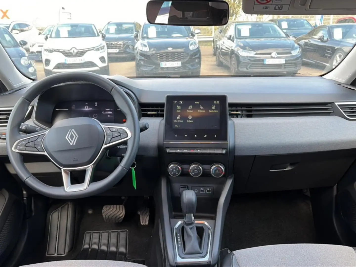 Vue intérieure avant de la Renault Clio V 1.0 TCe 90 Evolution, tableau de bord gris avec écran tactile et volant multifonction.