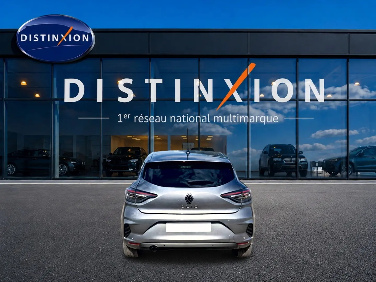 Vue arrière d'une Renault Clio V gris foncé garée devant une vitrine avec logo Distinxion.