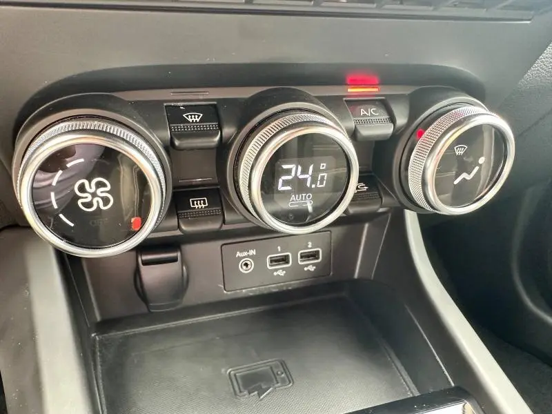 Gros plan sur les commandes de climatisation digitale du Renault Arkana noir métal, affichant 24°C et boutons rétroéclairés.