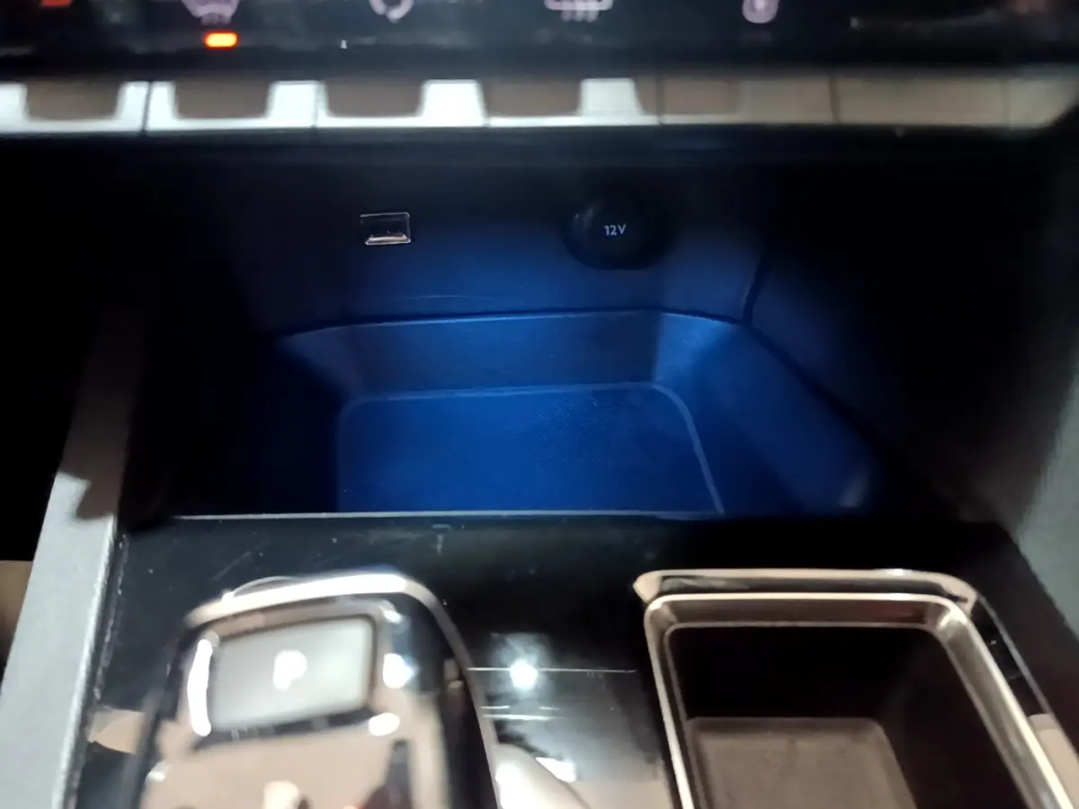 Gros plan sur la console centrale noire du Peugeot 3008 gris foncé, avec sélecteur de boîte automatique et prise 12V visible.