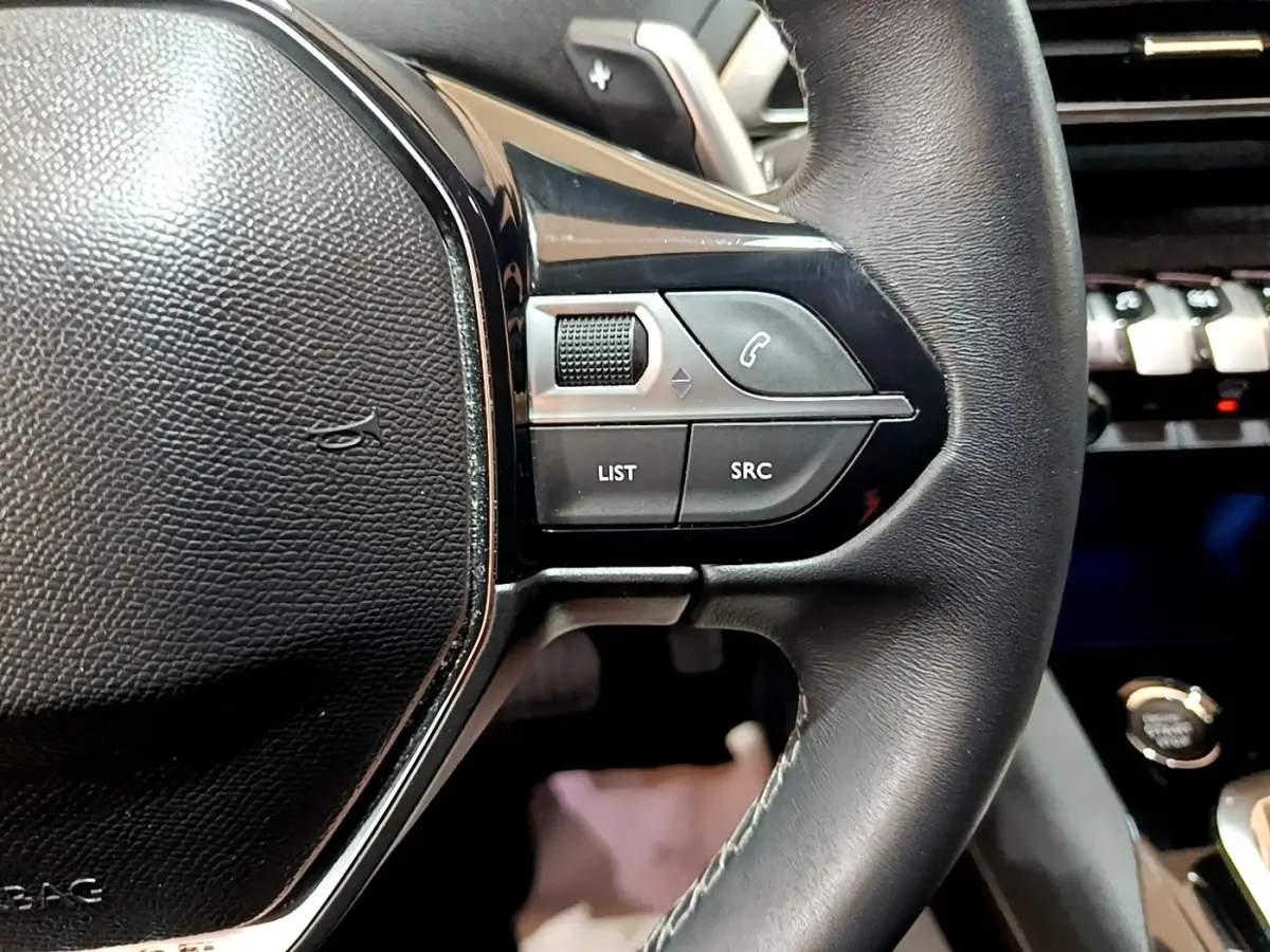 Gros plan sur les commandes gauche du volant cuir noir du Peugeot 3008 2022 BlueHDi Allure Pack.